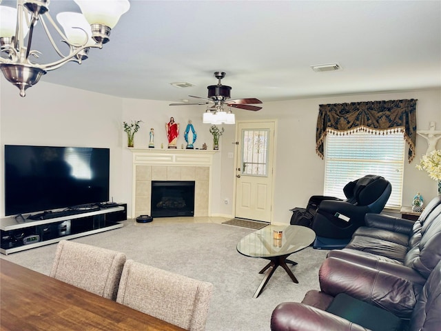 living room featuring ceiling fan with notable chandelier, carpet, and a tile fireplace