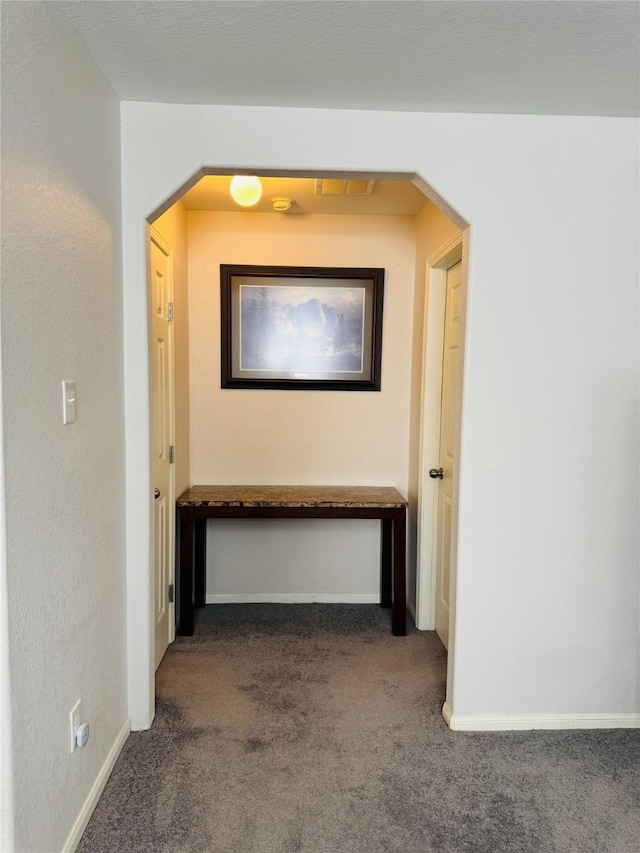 hall with dark colored carpet