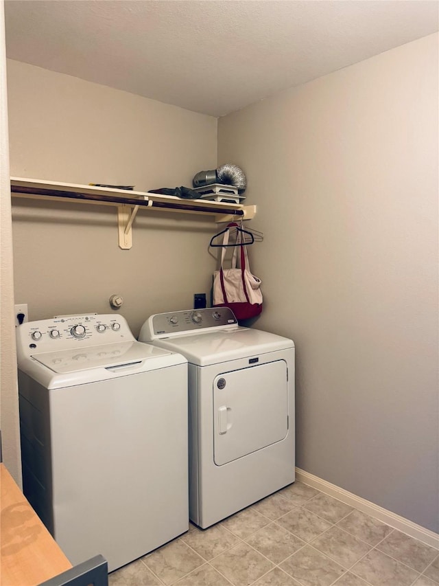 clothes washing area featuring washing machine and dryer and light tile patterned floors