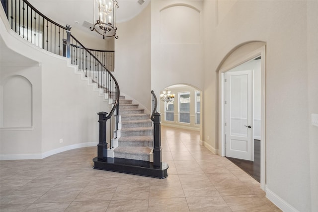 tiled entryway featuring a high ceiling, ornamental molding, and a chandelier