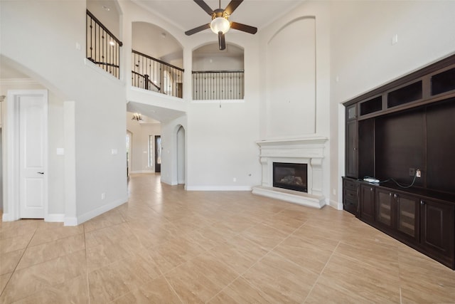 unfurnished living room with light tile patterned floors, ornamental molding, and ceiling fan