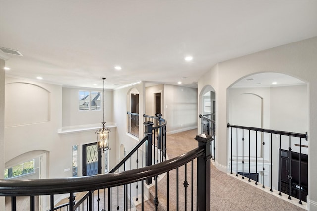 hall featuring light colored carpet and an inviting chandelier