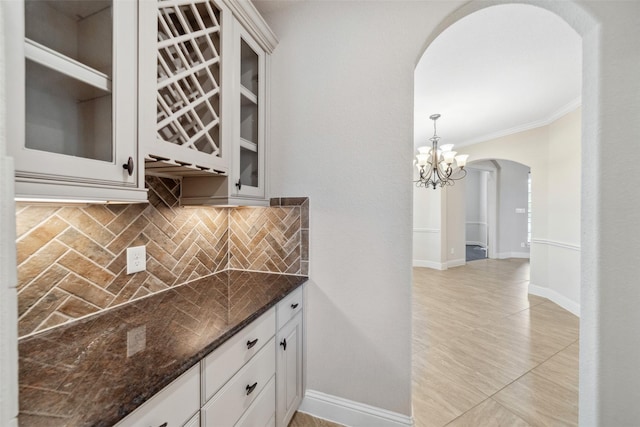 kitchen with white cabinetry, decorative light fixtures, ornamental molding, and decorative backsplash