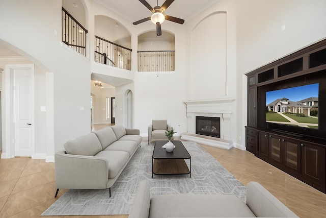 19031 Kimber Creek Ln, Cypress, TX 77429 - tiled living area with a towering ceiling, a glass covered fireplace, ceiling fan, arched walkways, and baseboards
