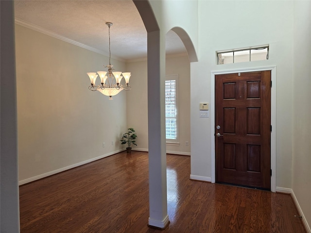 foyer with dark hardwood / wood-style flooring, a notable chandelier, and crown molding