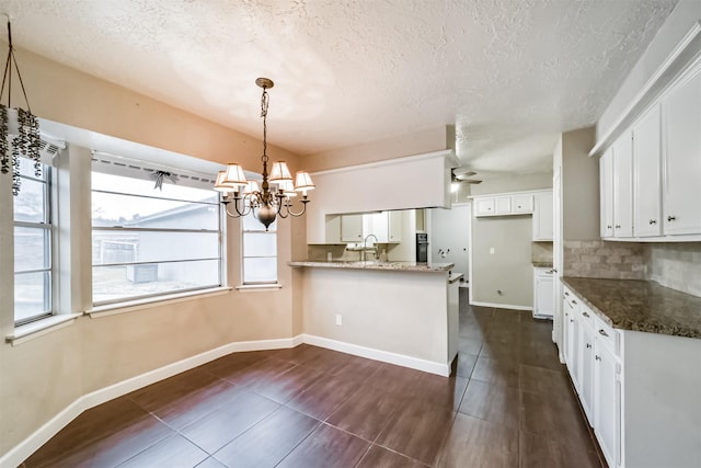 kitchen featuring dark stone countertops, decorative backsplash, kitchen peninsula, and white cabinets