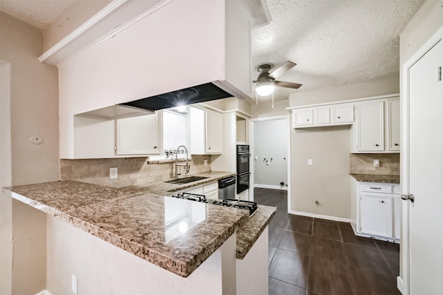 kitchen featuring stone countertops, sink, a textured ceiling, white cabinets, and kitchen peninsula