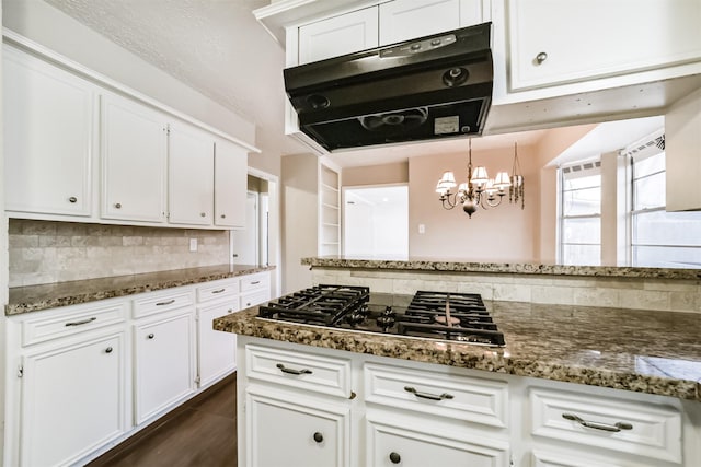 kitchen featuring white cabinetry, decorative backsplash, decorative light fixtures, dark stone counters, and stainless steel gas stovetop