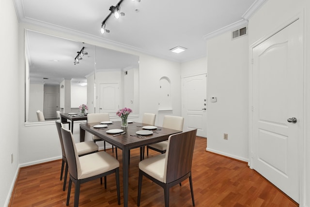 dining room with ornamental molding, rail lighting, and wood-type flooring