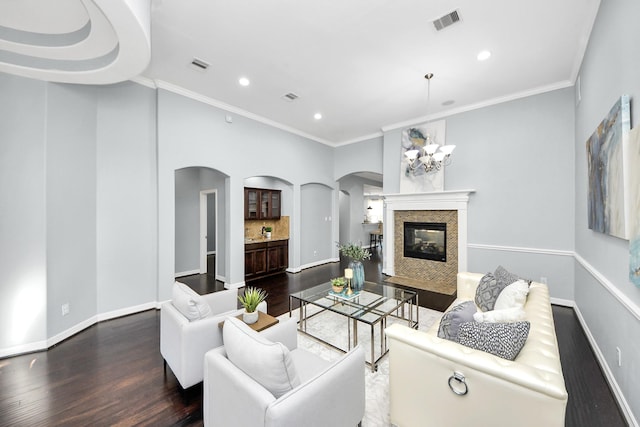 living room with dark hardwood / wood-style flooring, crown molding, a high end fireplace, and an inviting chandelier