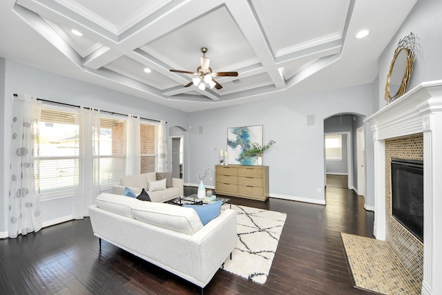 living room with coffered ceiling, a fireplace, dark wood-type flooring, and beamed ceiling