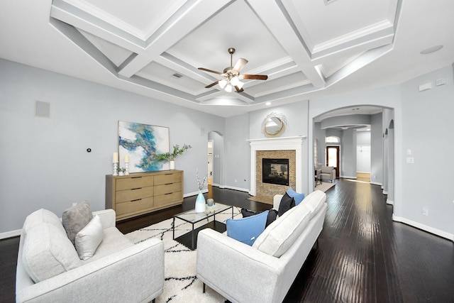 living room featuring coffered ceiling, dark hardwood / wood-style floors, beamed ceiling, ceiling fan, and a premium fireplace