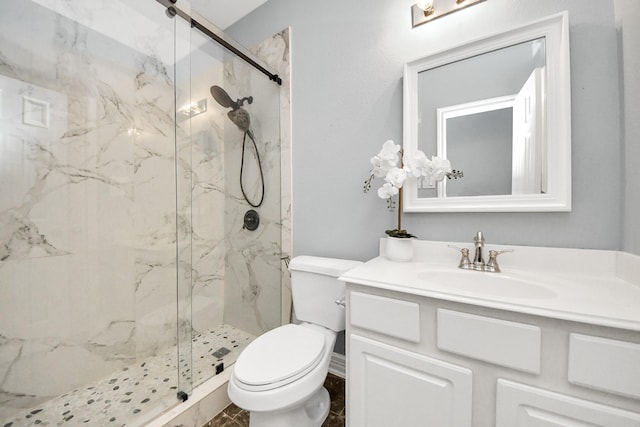 bathroom featuring a shower with door, vanity, and toilet