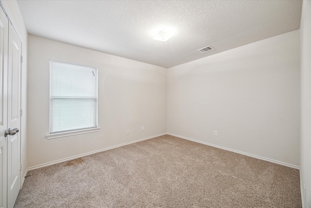 spare room featuring a textured ceiling and carpet