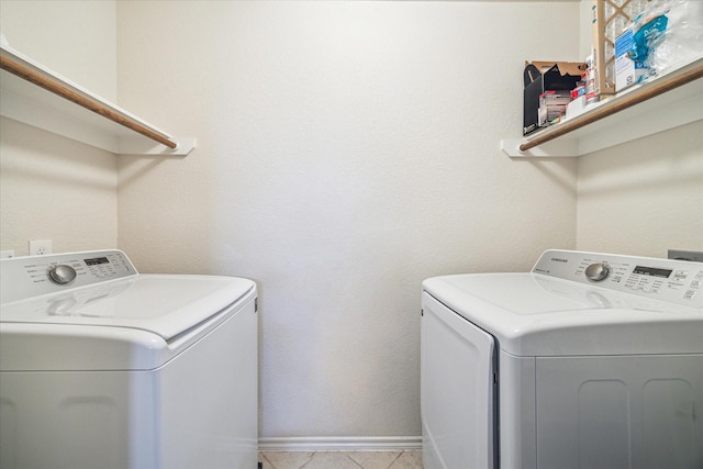 clothes washing area featuring light tile patterned floors and washing machine and clothes dryer