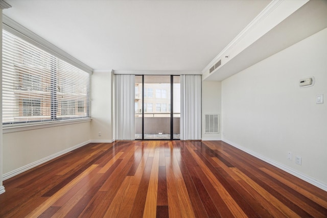 empty room featuring ornamental molding, a healthy amount of sunlight, and dark hardwood / wood-style floors