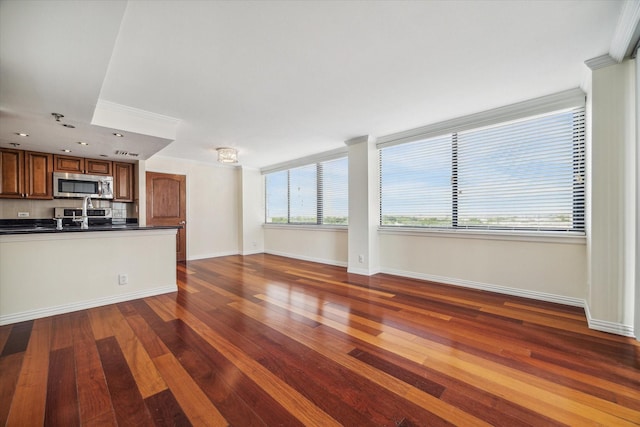 unfurnished living room with dark wood-type flooring, crown molding, and sink