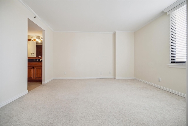 carpeted spare room with crown molding, sink, and a notable chandelier