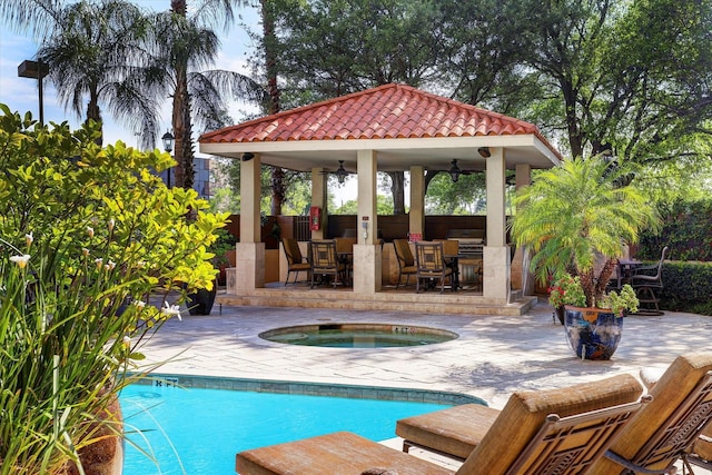 view of pool featuring a bar, an in ground hot tub, ceiling fan, a gazebo, and a patio area