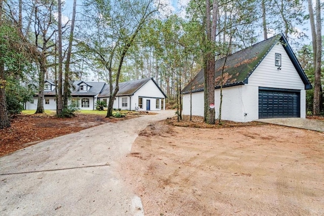 view of front facade with brick siding, a garage, driveway, and an outdoor structure