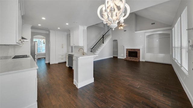 kitchen featuring a fireplace, decorative light fixtures, white cabinetry, a notable chandelier, and stainless steel appliances