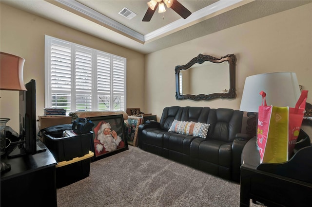 carpeted living room featuring a tray ceiling, ornamental molding, and ceiling fan