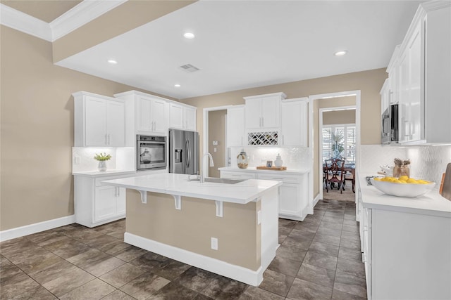 kitchen featuring sink, stainless steel appliances, an island with sink, and white cabinets