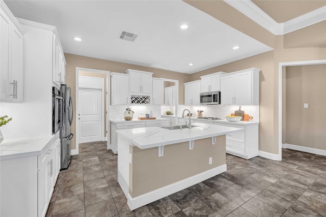 kitchen with sink, white cabinets, backsplash, a kitchen island with sink, and stainless steel appliances