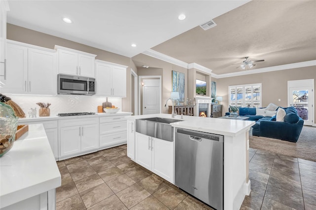 kitchen with sink, appliances with stainless steel finishes, tasteful backsplash, white cabinets, and a center island with sink