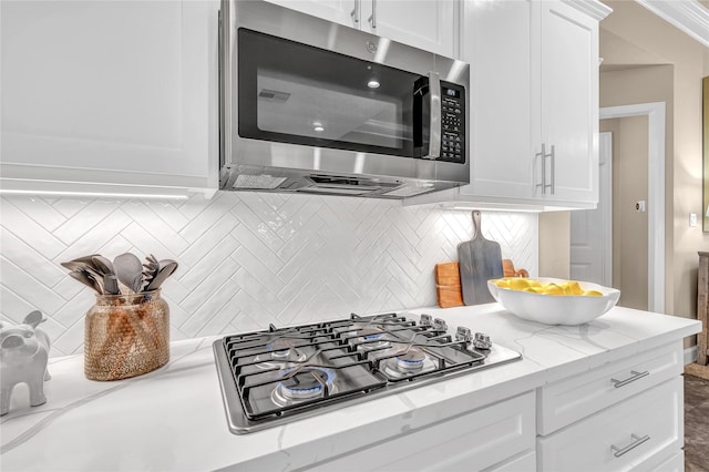 kitchen featuring light stone counters, appliances with stainless steel finishes, decorative backsplash, and white cabinets