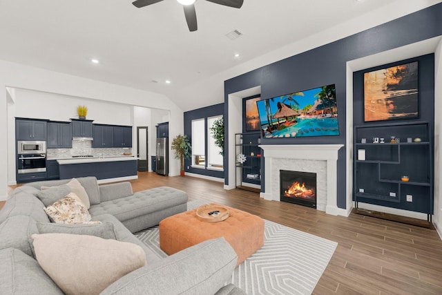 living room with wood-type flooring, lofted ceiling, and ceiling fan