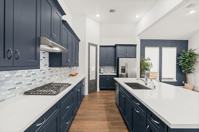 kitchen with stainless steel appliances, light stone countertops, sink, and backsplash