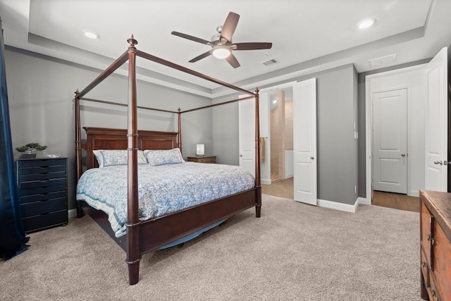 carpeted bedroom featuring ceiling fan and a raised ceiling