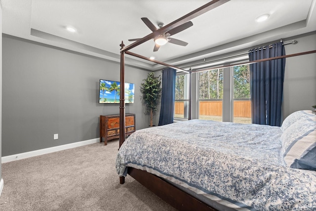 carpeted bedroom with a raised ceiling and ceiling fan