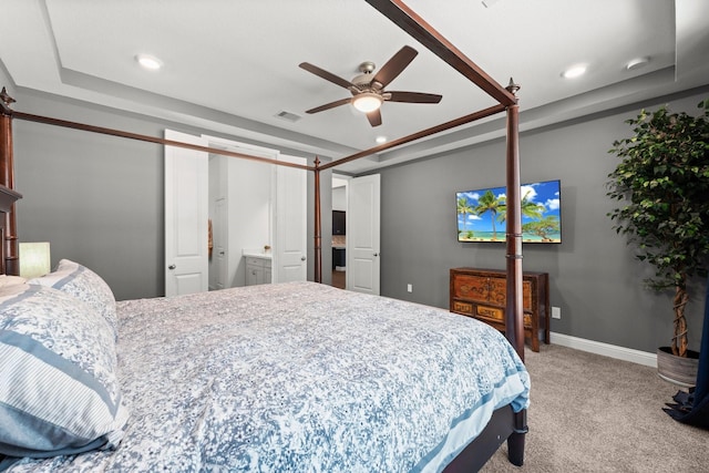 bedroom with light colored carpet, a raised ceiling, and ceiling fan