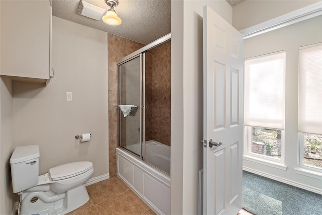 bathroom featuring toilet, tile patterned flooring, combined bath / shower with glass door, and a textured ceiling