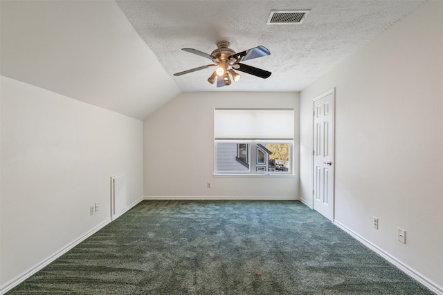 additional living space featuring lofted ceiling, ceiling fan, dark carpet, and a textured ceiling