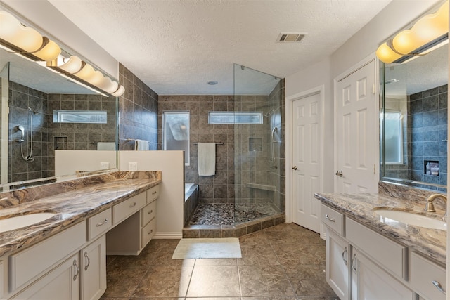 bathroom featuring vanity, a tile shower, and a textured ceiling