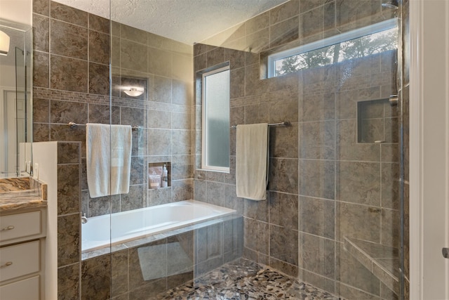 bathroom with vanity, independent shower and bath, and a textured ceiling