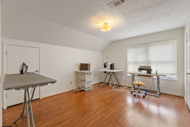 office space with wood-type flooring, vaulted ceiling, and a textured ceiling