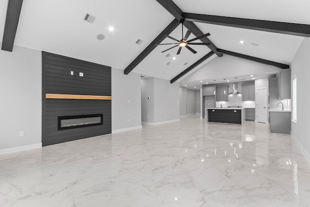 unfurnished living room with sink, beam ceiling, high vaulted ceiling, ceiling fan, and a fireplace