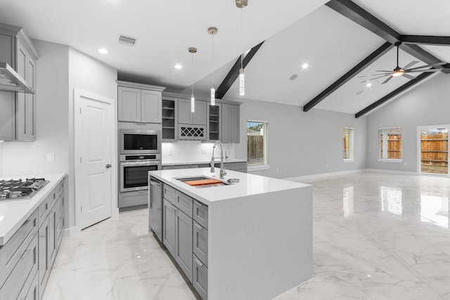 kitchen with gray cabinetry, sink, decorative light fixtures, and a center island with sink