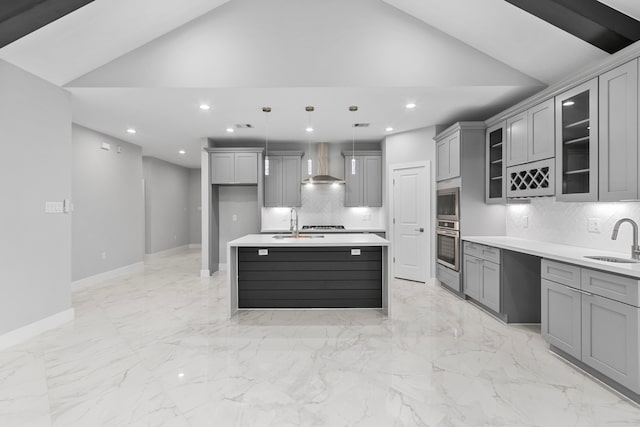 kitchen with lofted ceiling, wall chimney range hood, pendant lighting, gray cabinets, and sink