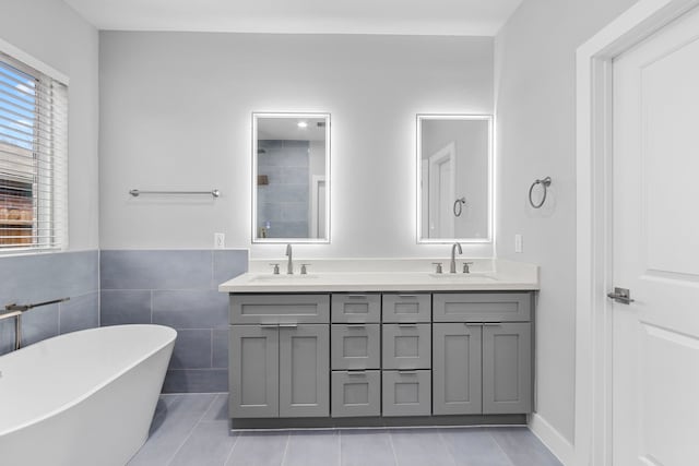 bathroom featuring vanity, a bath, tile patterned flooring, and tile walls