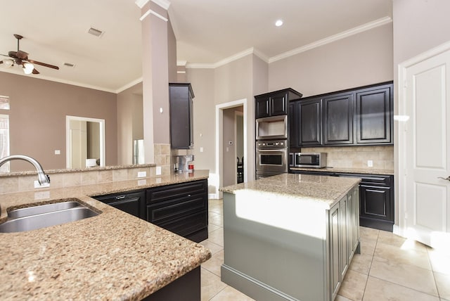 kitchen with ceiling fan, stainless steel appliances, a sink, dark cabinets, and backsplash