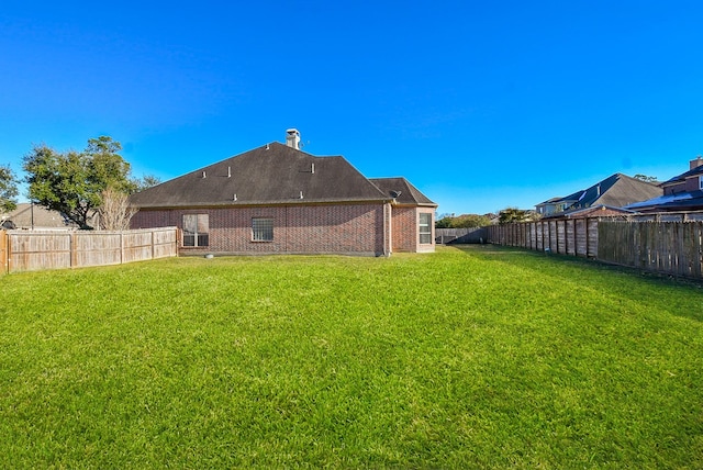 rear view of property with a lawn, brick siding, and a fenced backyard