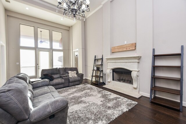 living room with a premium fireplace, crown molding, dark wood-type flooring, and a towering ceiling