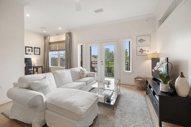 living room featuring crown molding, light hardwood / wood-style flooring, and french doors