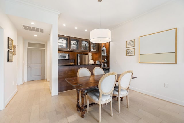 dining space with light hardwood / wood-style flooring and ornamental molding