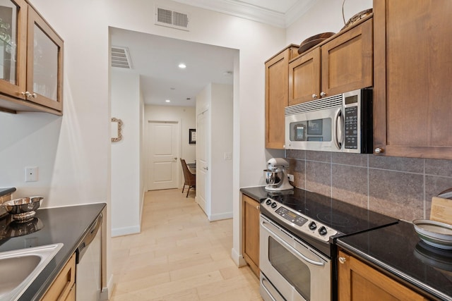 kitchen featuring sink, light wood-type flooring, ornamental molding, appliances with stainless steel finishes, and decorative backsplash